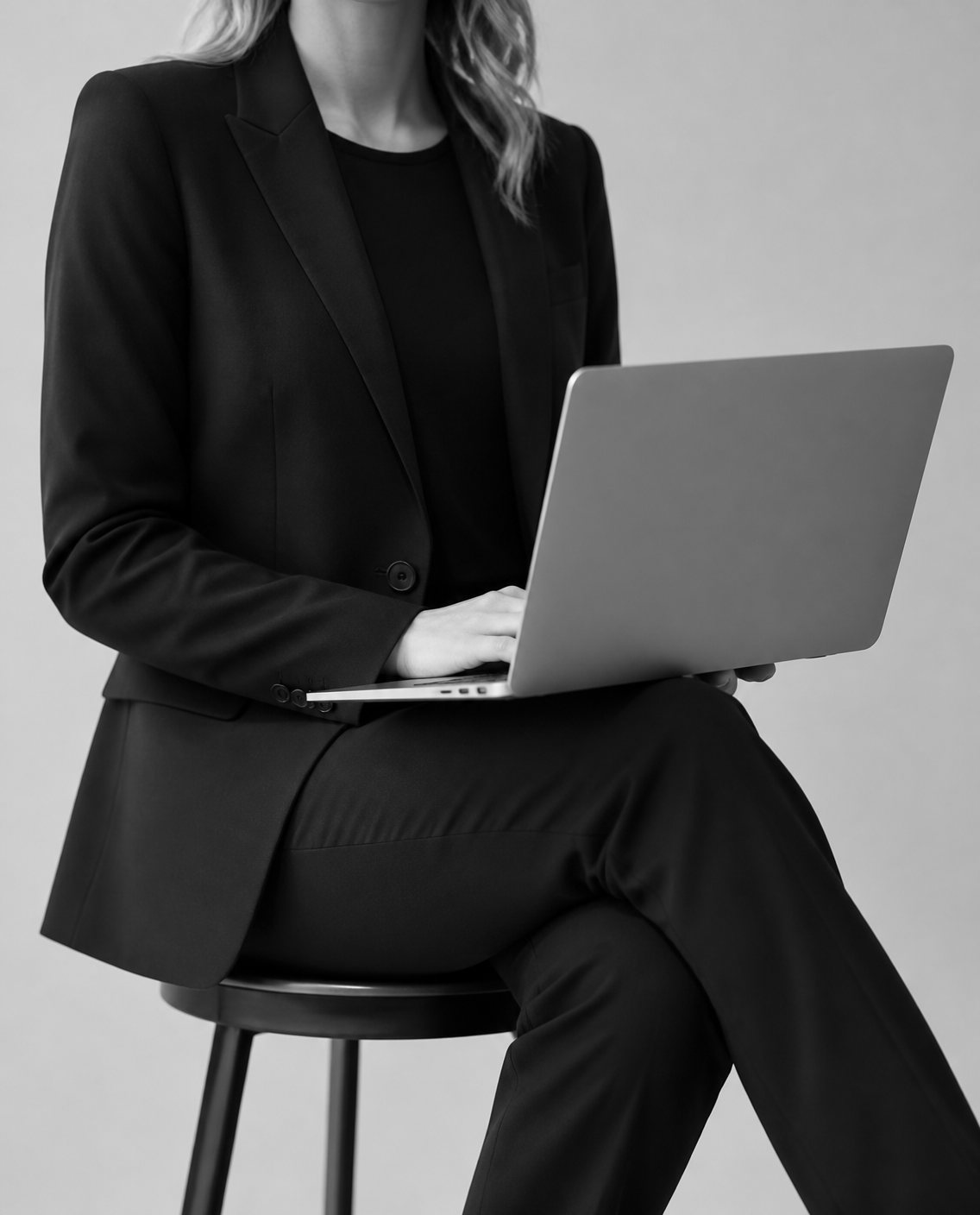 Professional in a black suit working on a laptop